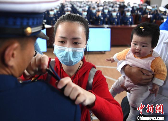新消防員楊振的妻子彭莉與女兒現(xiàn)場見證丈夫加入“火焰藍(lán)”的神圣時刻?！⒅铱?攝