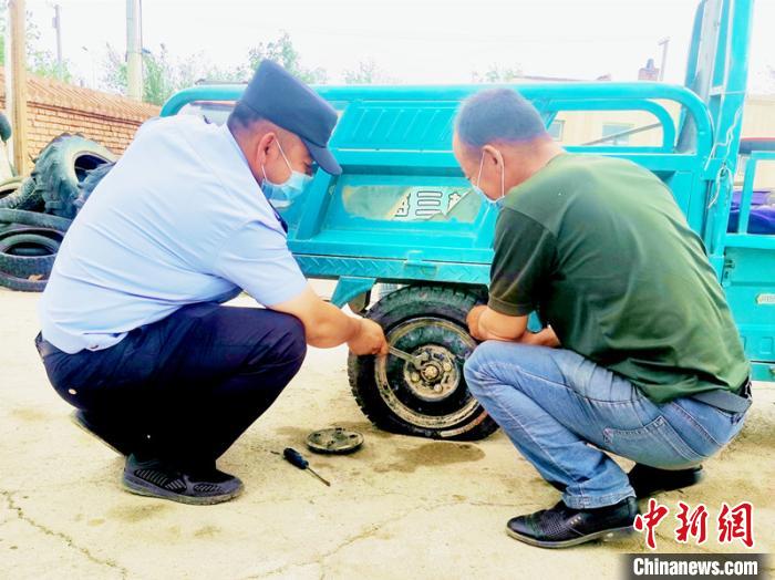 賽旦與民警共同維修三輪摩托車。　依力哈木江 攝